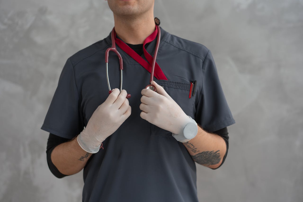 Close-up of a medical professional in scrubs with stethoscope and latex gloves.